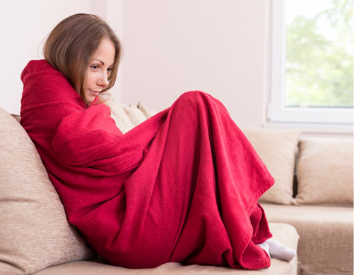 A woman wrapped up in a blanket considering calling ckSmithSuperior for Emergency Heating Service